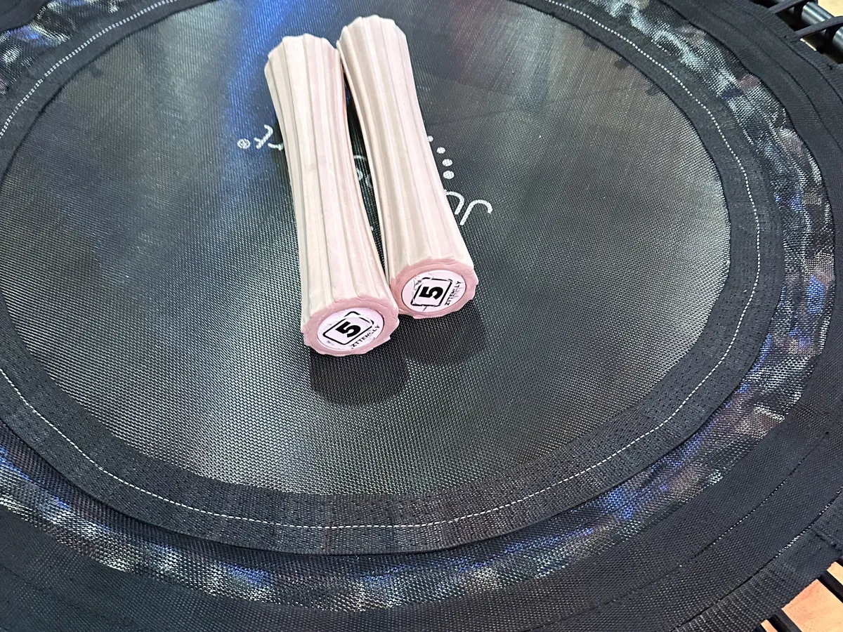Weighted workout bars resting on a mini trampoline for REbound + Sculpt