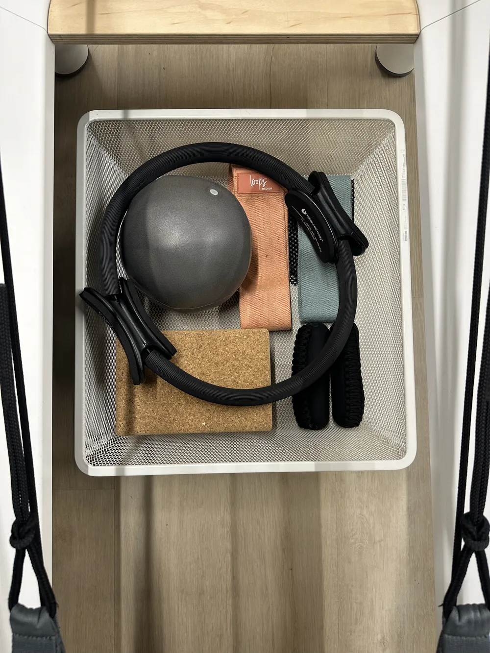 Basket of Pilates props — magic circle, ball, cork blocks, and resistance bands